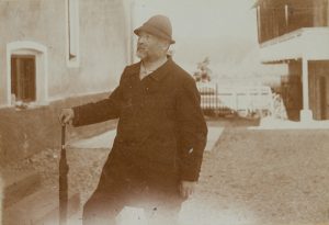 Mann mit Schirm und Hut im Hof