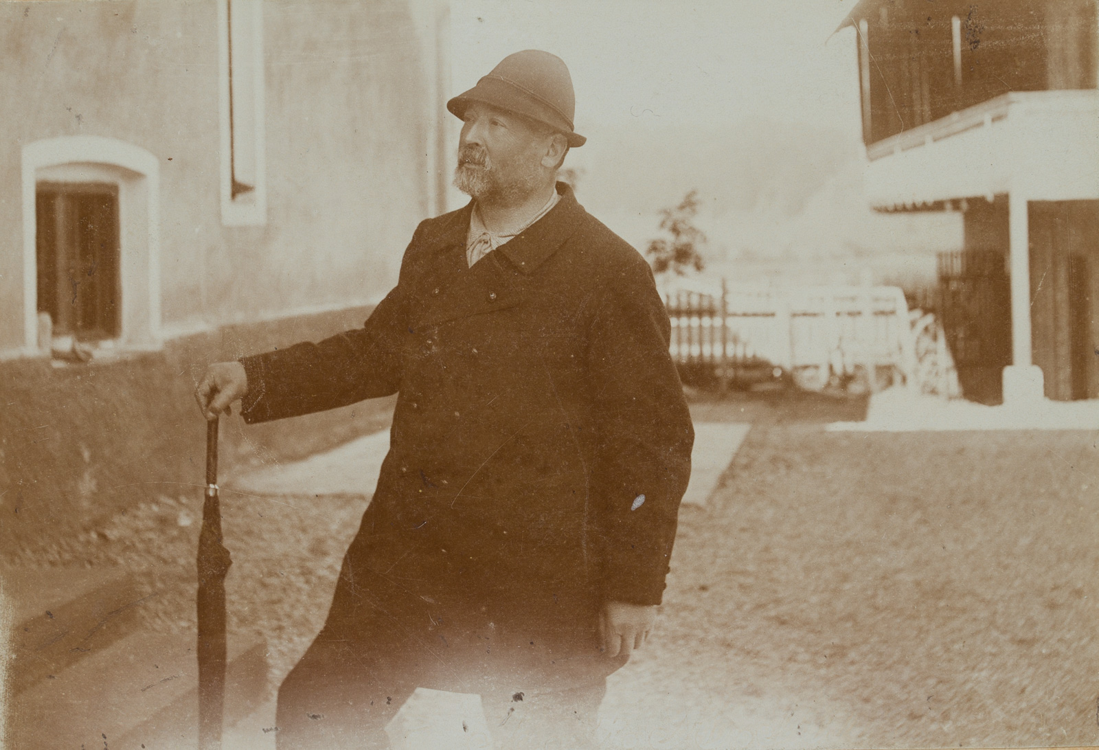 Mann mit Schirm und Hut im Hof
